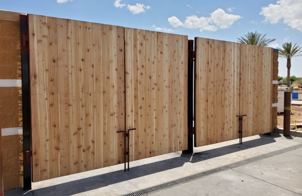 Steel-framed commercial dumpster gate with cedar panels fabricated by American Welding